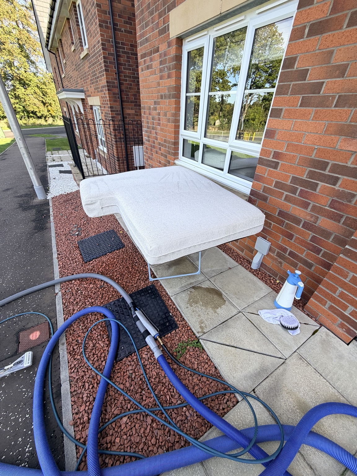 Removable bouclé sofa section being professionally cleaned outside using the truck-mounted extraction system